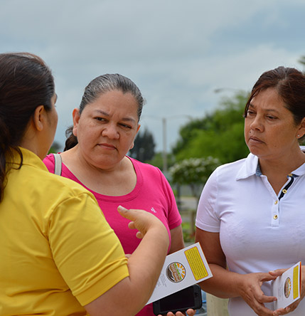 A promotora talks with community members.