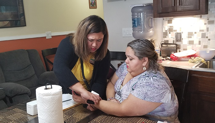 Chronic Disease A CHW helping a woman check her heart rate..