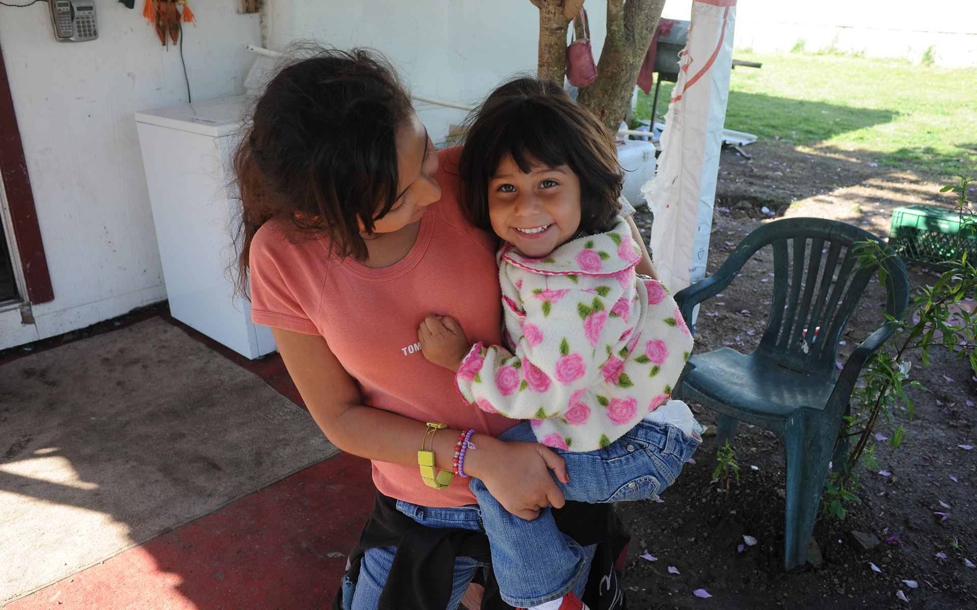 A young girl from the colonias holding her baby sister.