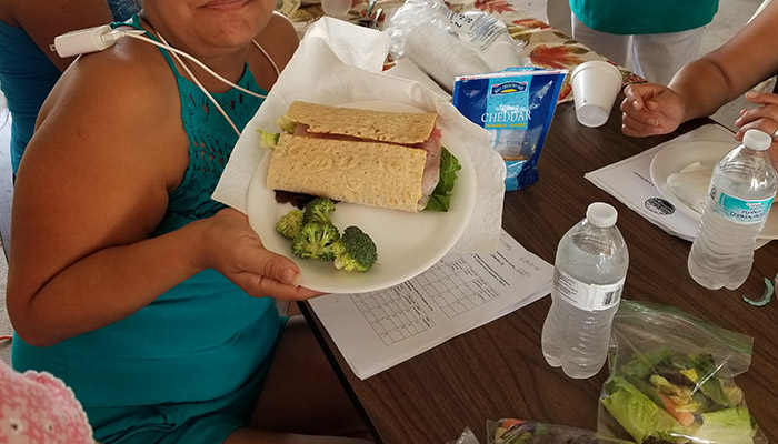 A women holding a plate of broccoli and healthy wrap.