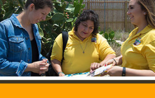 Two CHWs showing a community member a pamphlet