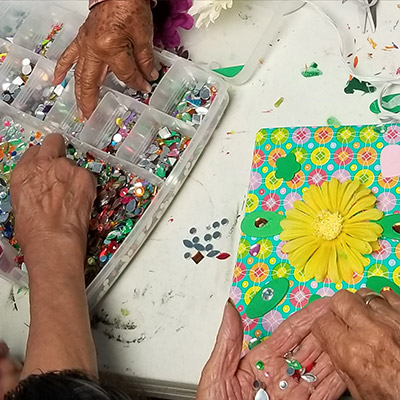 Hands decorating notebooks with beads.