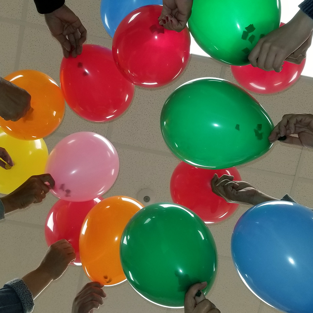 Women holding up balloons of different colors.