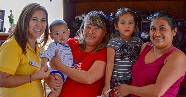 A CHW poses with two mothers and their children.